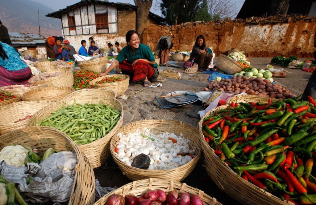 Women selling chillies, beans and vegetables from baskets at an open-air village market in Bhutan