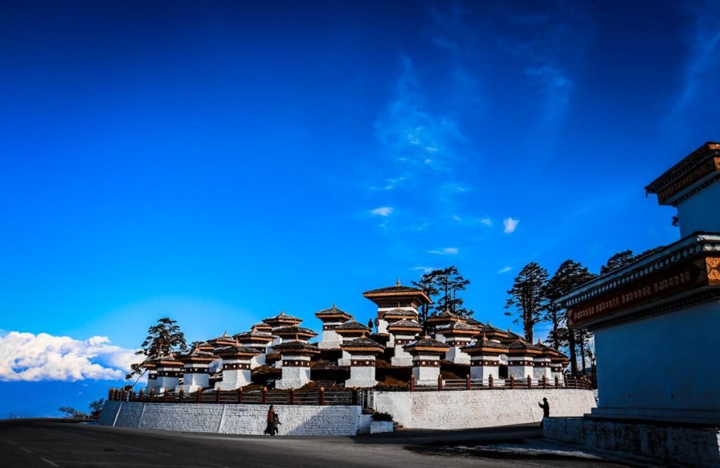 The chortens at Dochula pass under a deep blue sky with forest behind