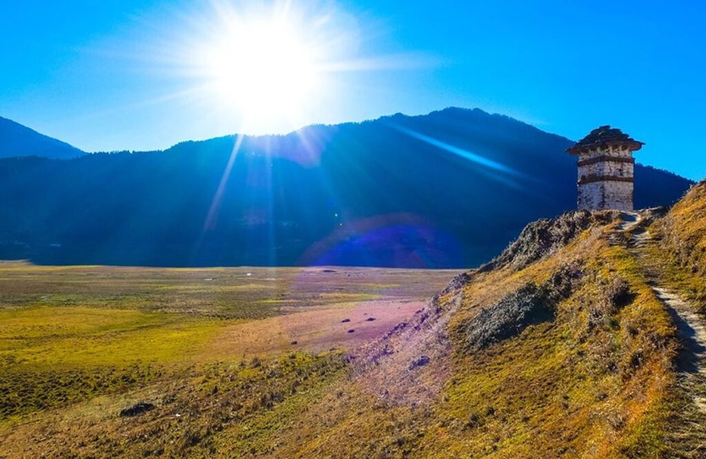 Sun bursting over a ridge above the broad open floor of the Gangtey valley