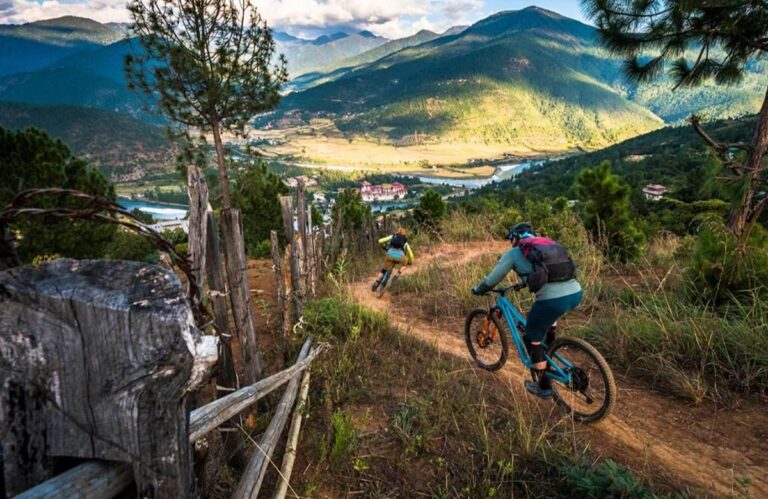 A mountain biker riding a singletrack trail on a hillside above a Bhutanese valley