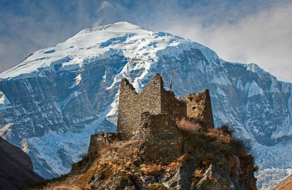 A ruined stone fort on a moraine below a large snow-covered peak