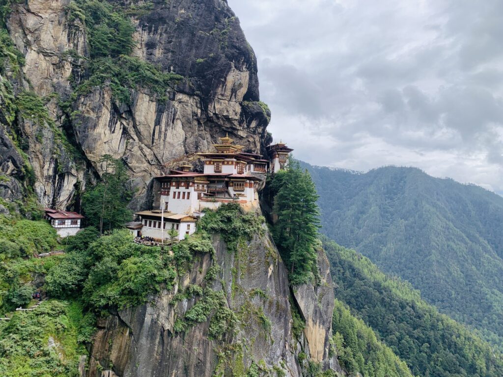 Paro Taktsang seen along the cliff, forested ridges stretching into the distance