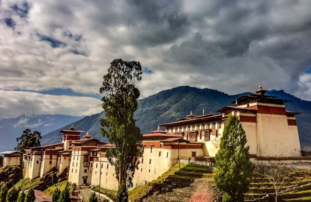 The long terraced roofs of Trongsa Dzong spread along a ridge under heavy cloud