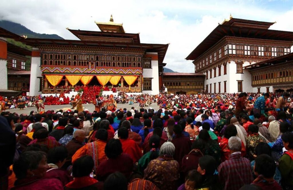A dense crowd in traditional dress filling a dzong courtyard for a tshechu festival