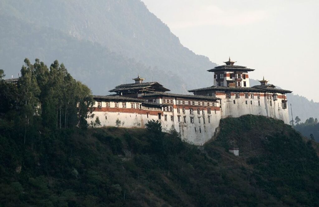 Wangdue Phodrang Dzong on a narrow ridge above the valley, framed by forest