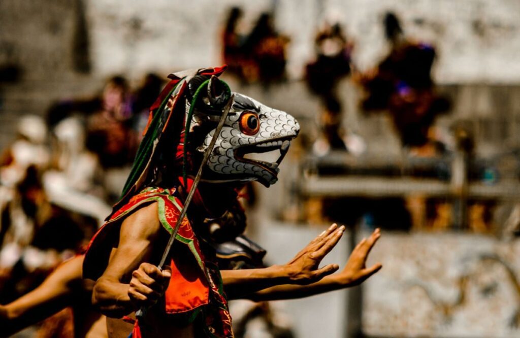 Close-up of a dancer in a white animal mask with a carved wooden headdress
