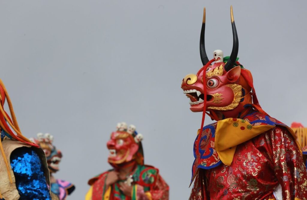 A dancer wearing a red horned wrathful-deity mask at a tshechu